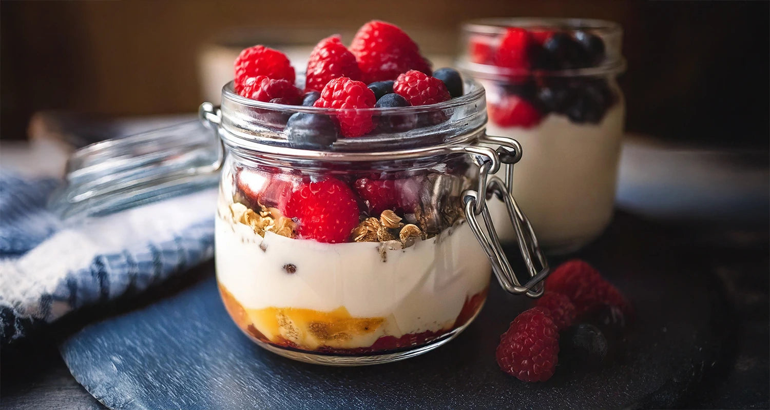 Rote Beeren mit Knuspermüsli auf Naturjoghurt und Honig, im Einmachglas
