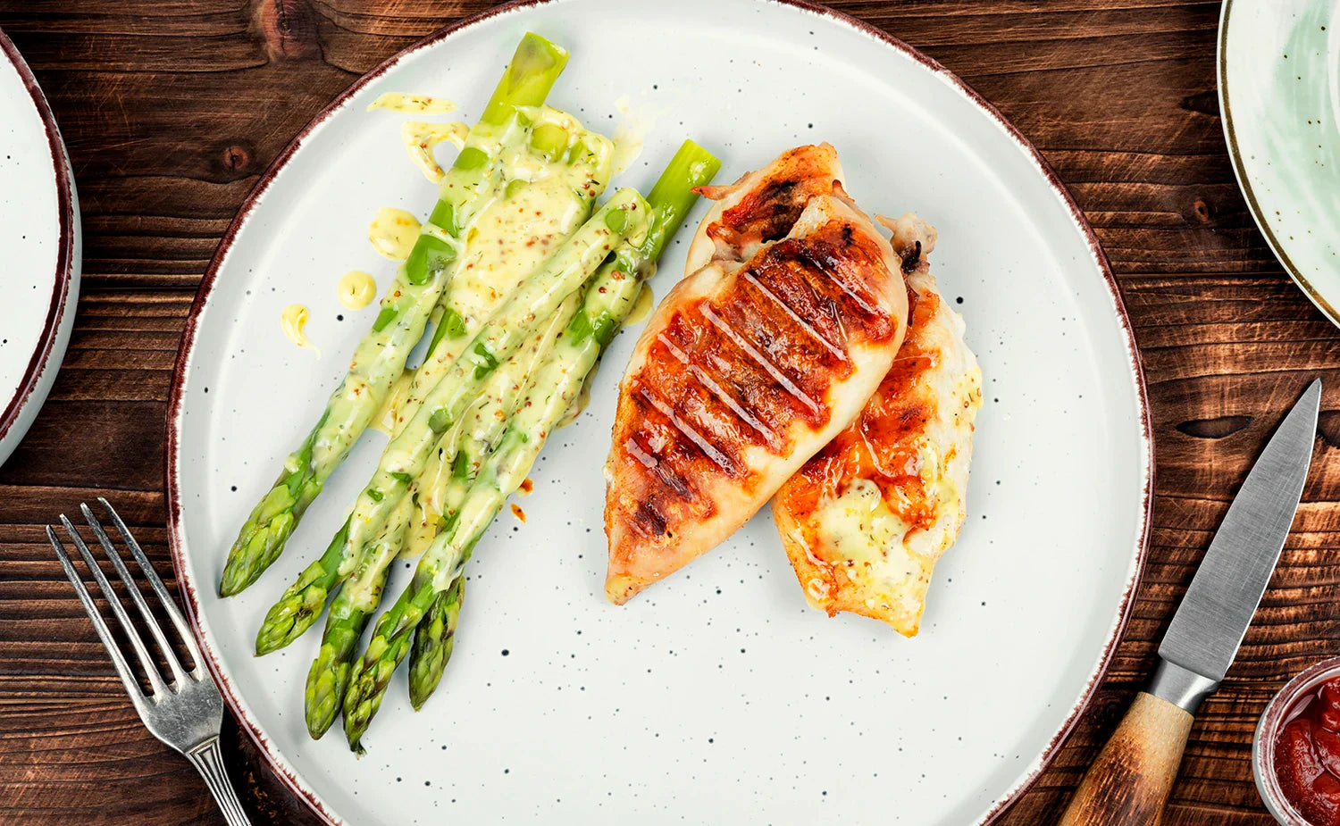 Zitronen-Hähnchen mit grünem Spargel, angerichtet auf einem weißen Teller, mit Zitronensaft verfeinert – gesundes und leichtes Frühlingsgericht.
